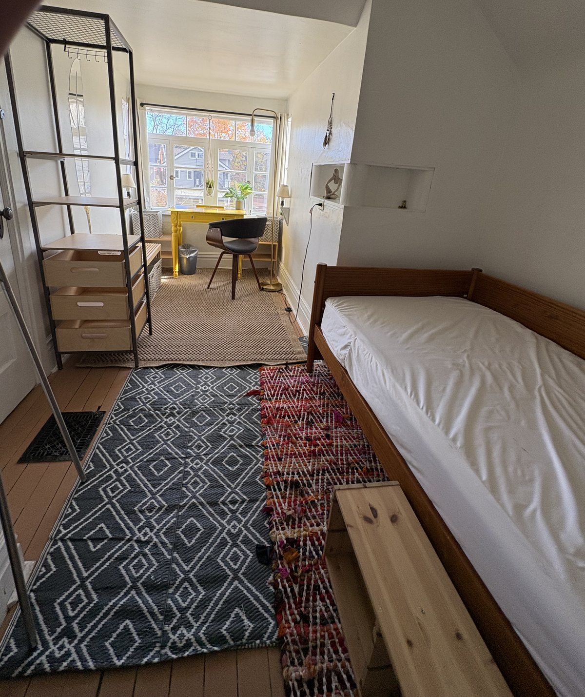 Third floor east-facing room with a yellow desk at the window, open shelving and sloped ceilings